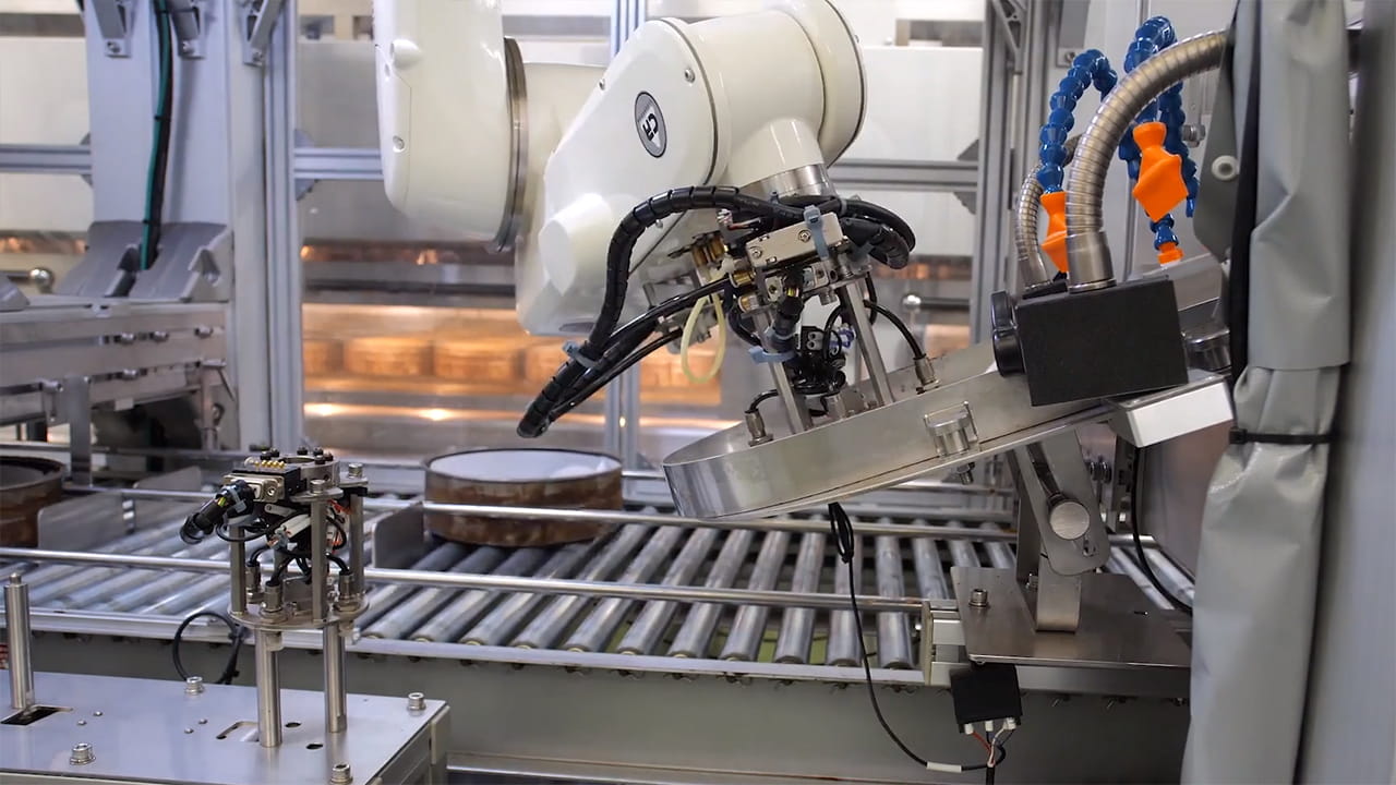 人手作業をロボットに置換え！ケーキ製造ラインでのクッキングシート挿入ロボット
