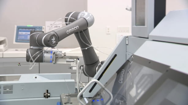製本機へのワーク投入工程を自動化し、オペレータ1名を専従作業から解放